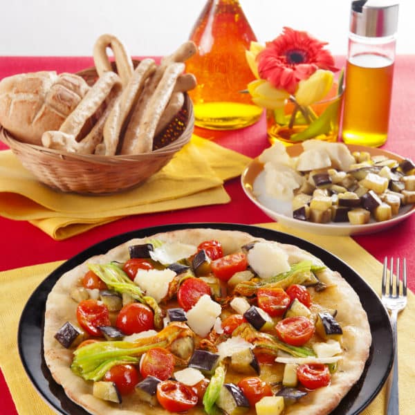 Mediterrane Pizza mit Kirschtomaten, Aubergine, Zucchiniblueten und Parmesan